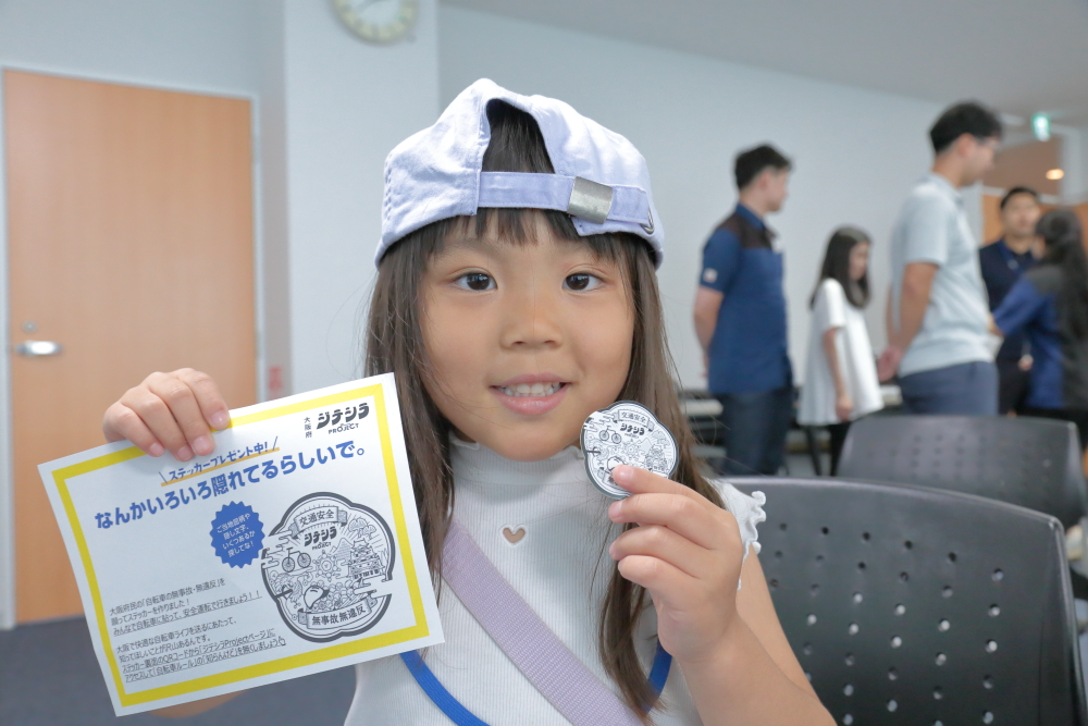 子どもが大阪府ジテシラProjectのステッカーを手に持って見せてくれる写真