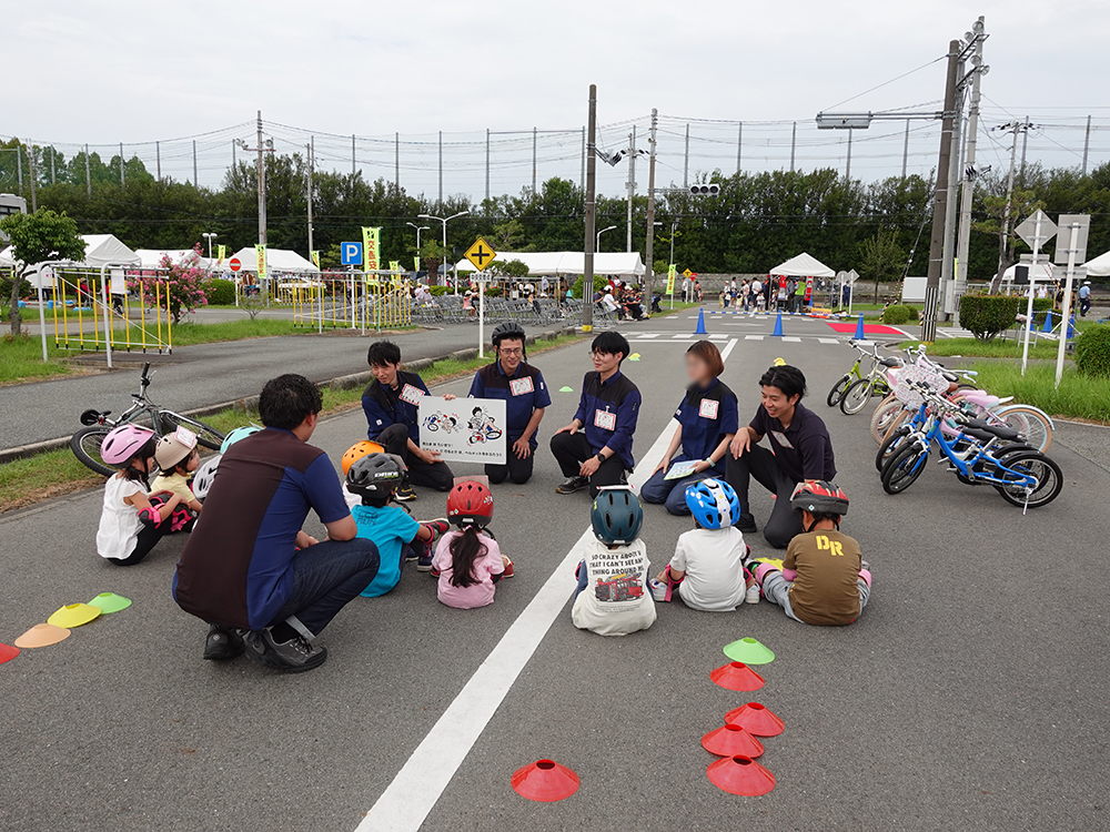 ヘルメットを着用した子どもたちが、自転車の安全ルールについて説明を受けている様子