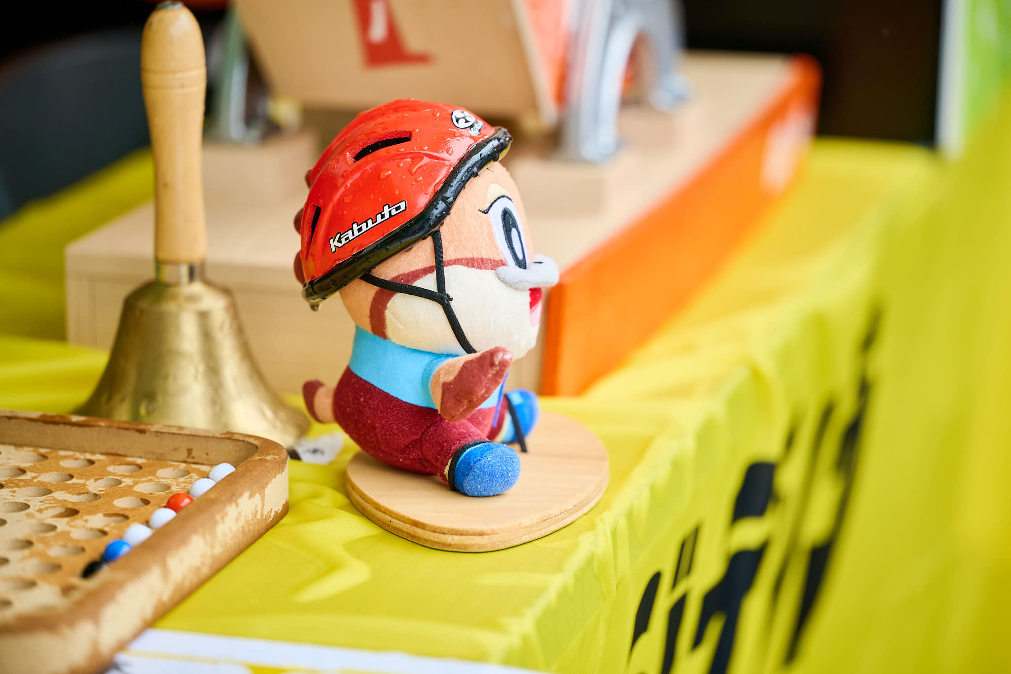 イベントブースのテーブルに置かれたキャラクター人形(ジテシラマスコットキャラクター もずやん)、赤いヘルメットを着用